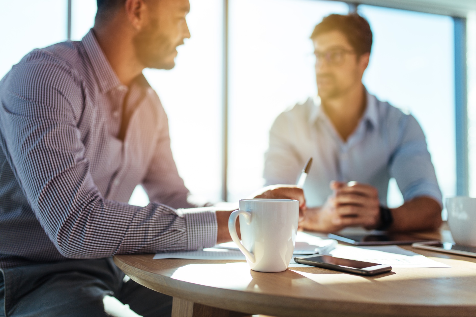 Deux hommes discutant autour d’un café, illustrant une session du coaching pack et un espace de dialogue.