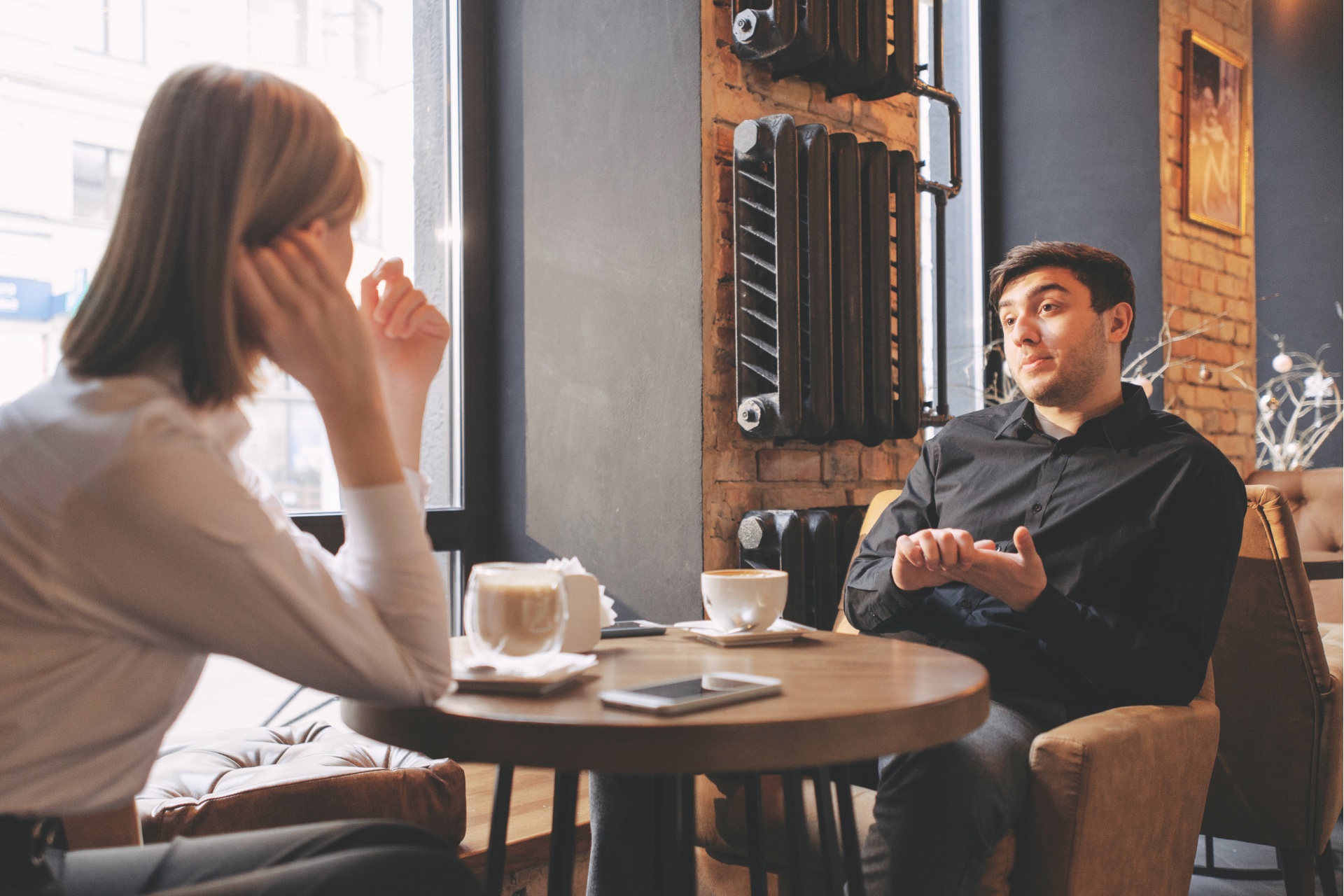 Une femme et un homme en pleine discussion dans un café, représentant une rencontre de coaching en présentiel.