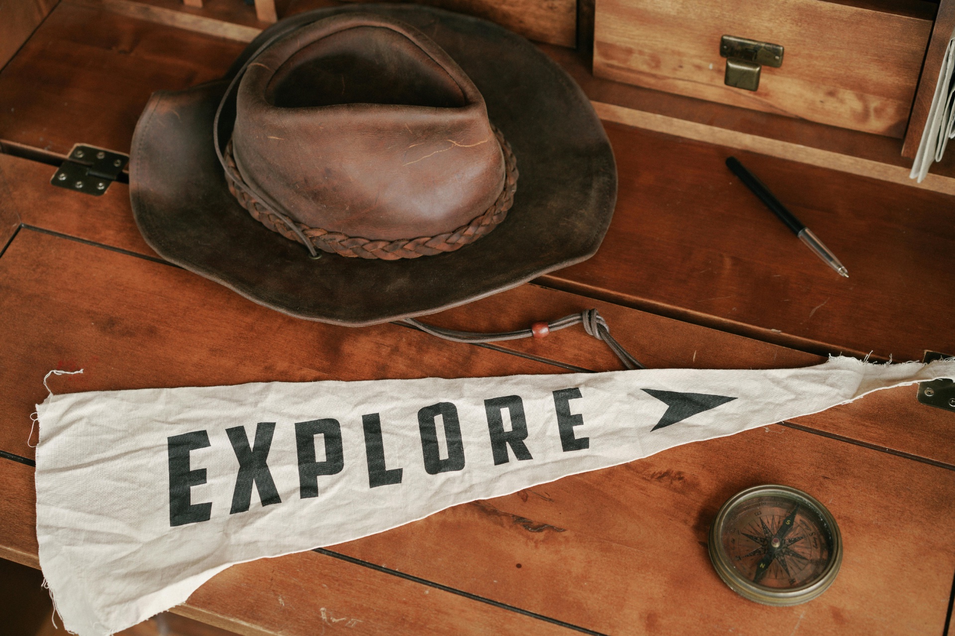 Leather hat, compass, and flag with the word Explore symbolizing career exploration in coaching programs